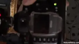 Blonde Oma in grünem Shirt steht vor Kommode